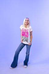 Woman in CHooZ FUN tee and flares standing confidently on purple backdrop