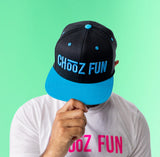 Man wearing black and blue “ChooZ FUN” flat brim Standout or Stand Back hat with green background
