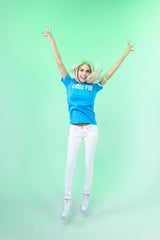 Woman jumping high in neon blue CHooZ FUN tee on green backdrop. The FUN Mark Tee – Neon Series brings bold energy, retro color, and high-vibe joy.