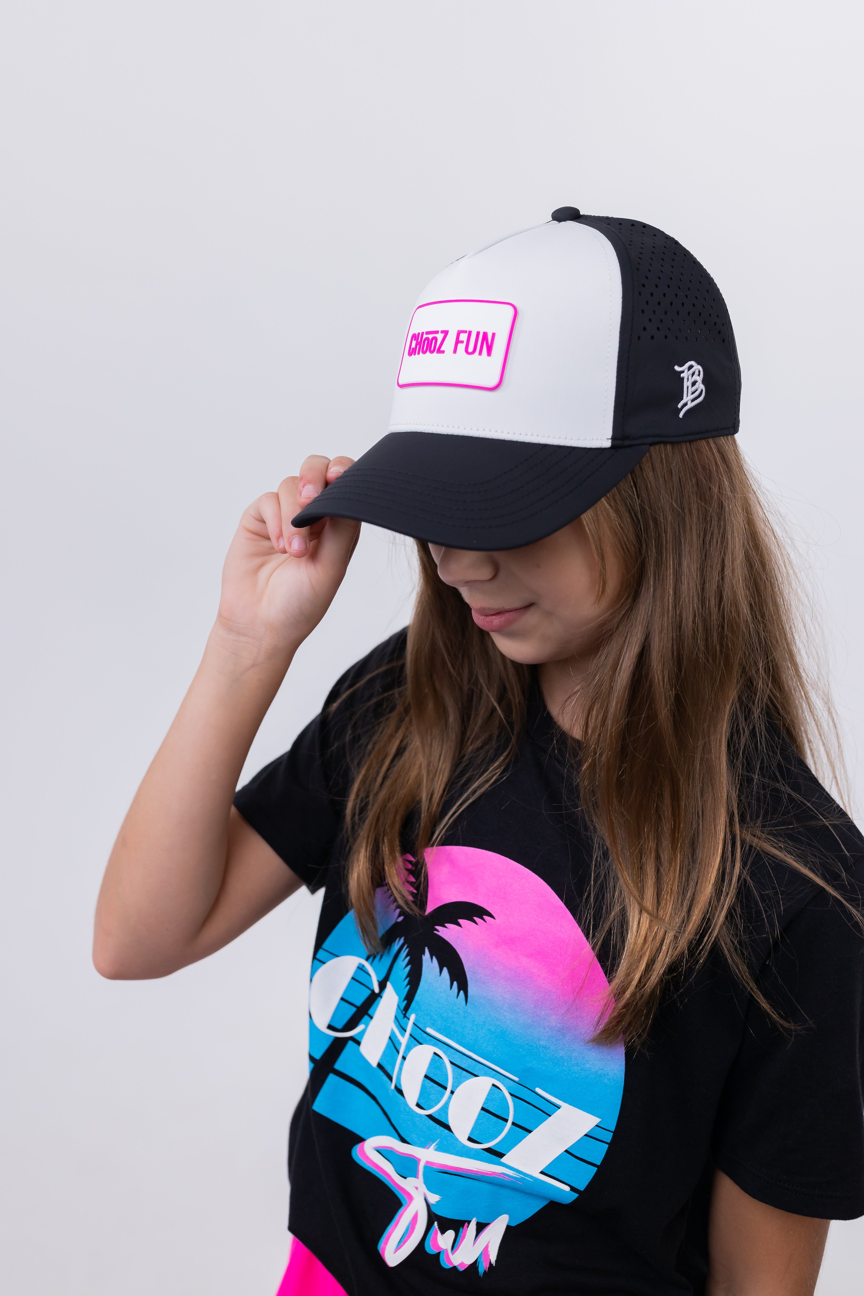 Girl in sunset tee adjusting Lil’ FUN Mark Hat – White with Pink Patch – side profile